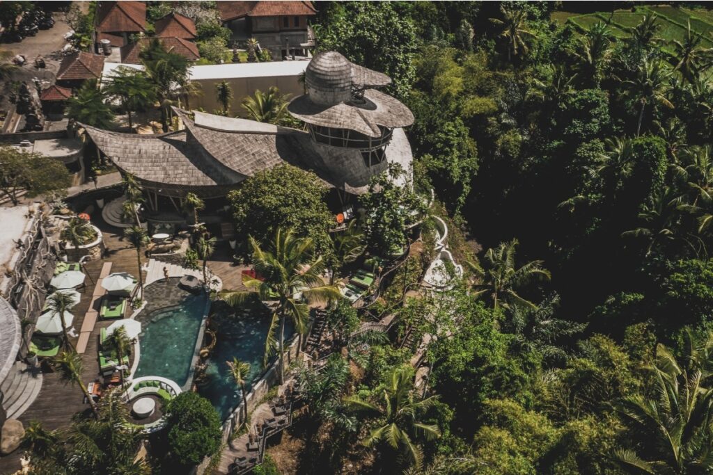 Aerial view of a Bali day club with pool, lounge areas, and jungle surroundings from morning to sunset.