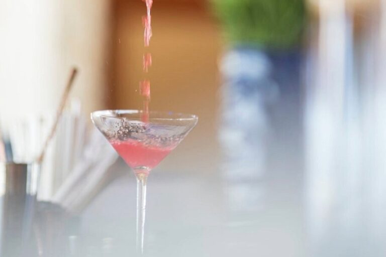 Pink cocktail being poured into a glass, showing a signature beach club drink served in Bali.