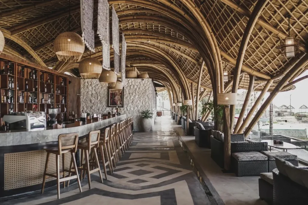 Open air beach club bar with bamboo roof, seating area, and ocean view in Bali.