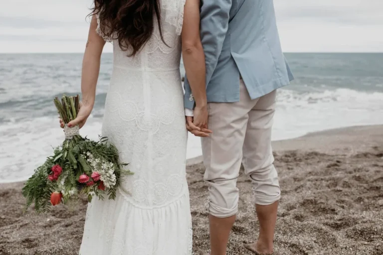 Couple holding hands on Bali beach during a romantic beachfront wedding moment.