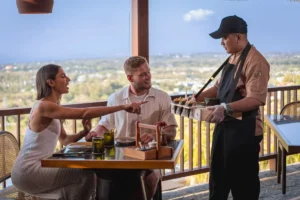 Couple enjoys dining in Uluwatu while a chef serves food with a hilltop view in Bali.
