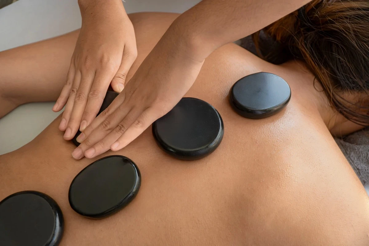 Therapist performs hot stone massage treatment on a guest during a relaxing spa session in Uluwatu.