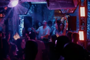 People dance around a DJ at a lively Bali nightclub, showing one of the island's popular party experiences.