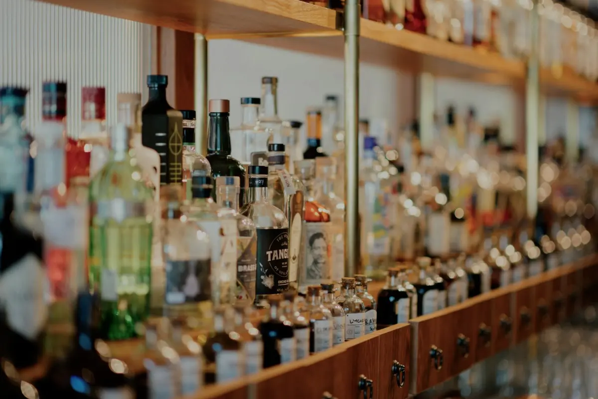 Berbagai botol minuman alkohol tersusun di rak bar, menunjukkan pilihan yang sering tersedia di beach club Bali.