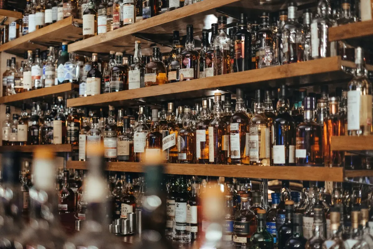 Rak berisi berbagai minuman alkohol di bar, menggambarkan pilihan minuman untuk liburan di Bali.