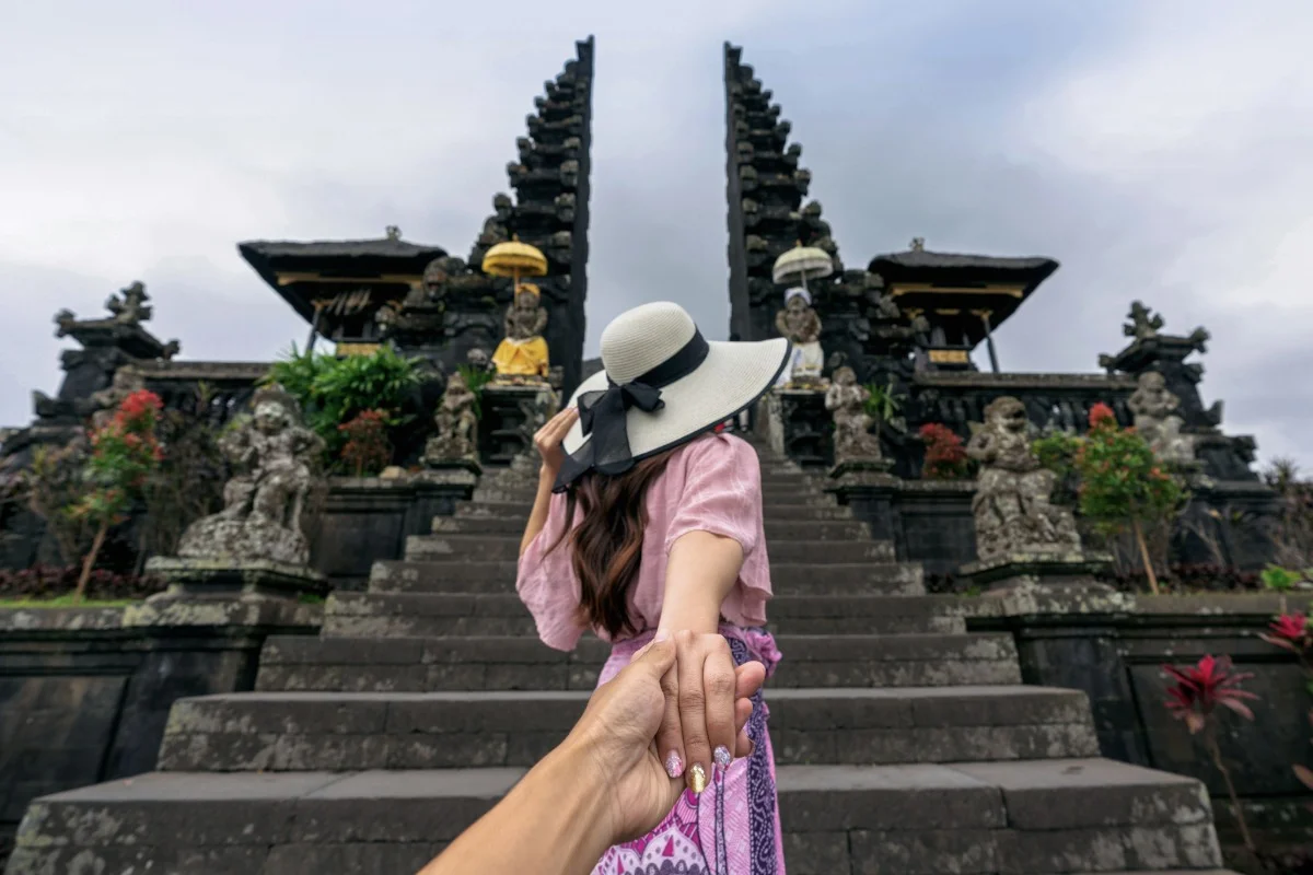 A traveler leads a companion up temple steps during a Bali day trip.