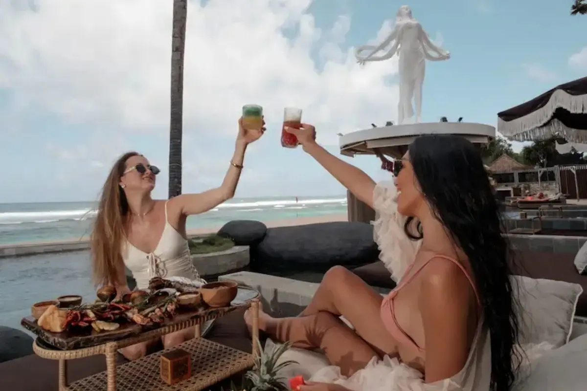 Two guests enjoy food and drinks at an oceanfront restaurant in Bali with relaxing sea views.