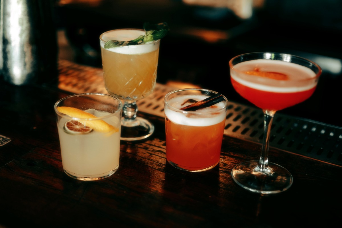 Four tequila cocktails with different garnishes show classic and modern drink styles served at a cocktail bar.