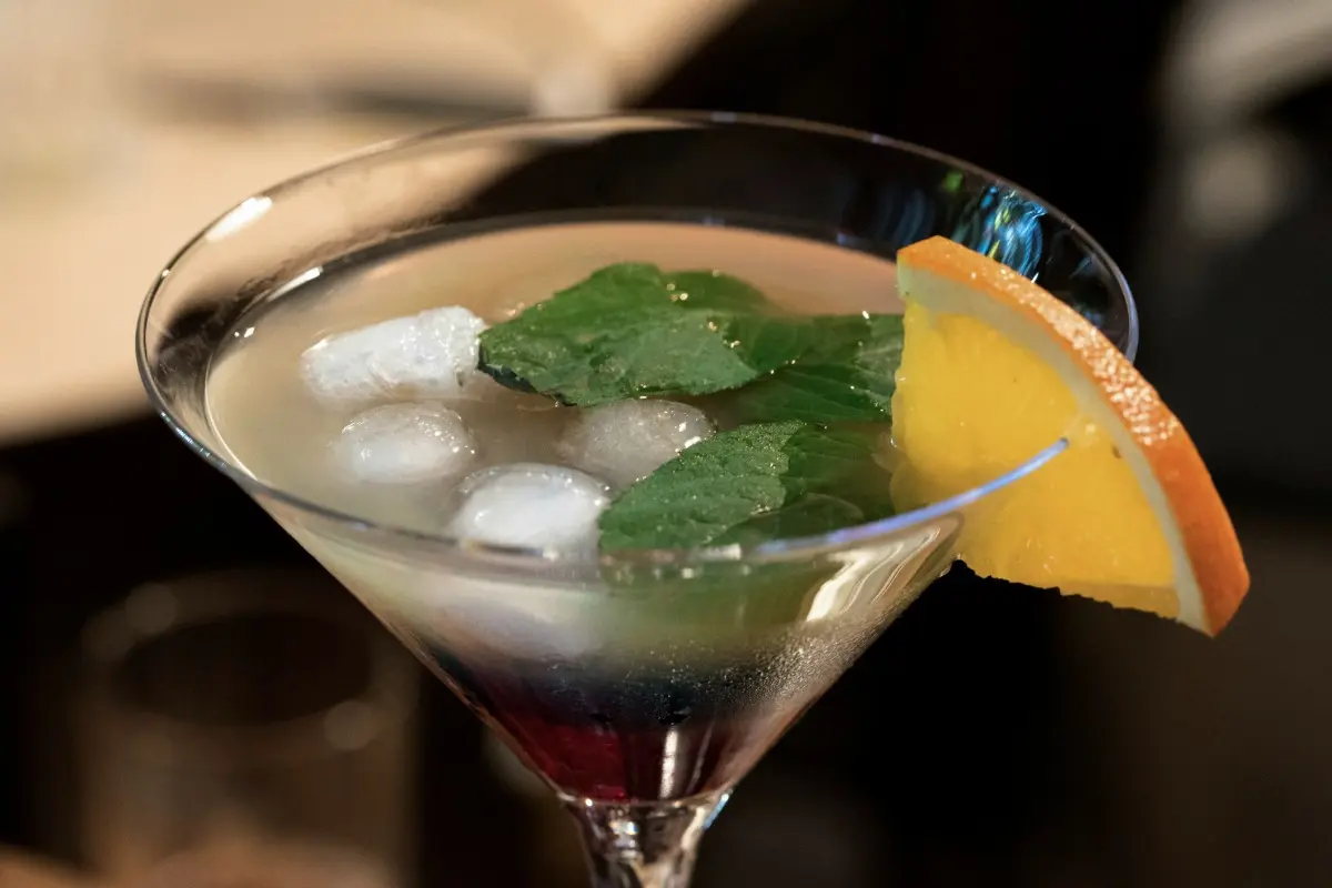 A tropical cocktail with mint, ice, and an orange slice, served for sunset drinks at a Bali beach club.